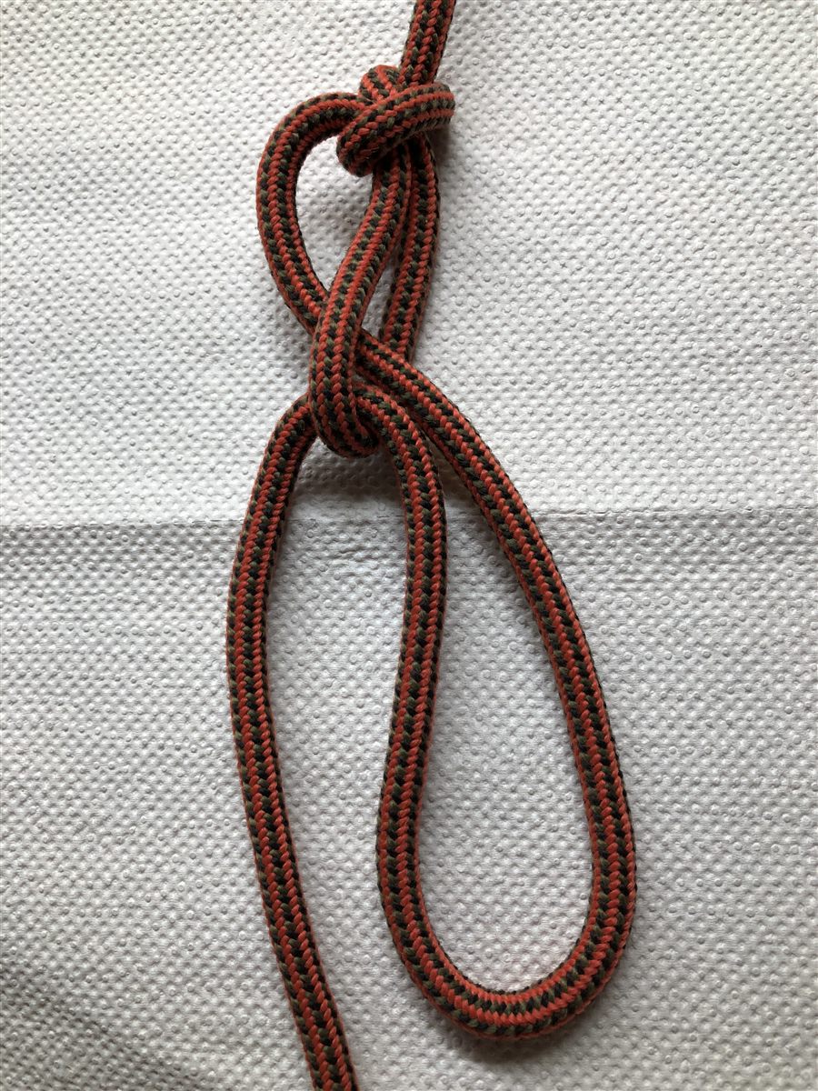 Photo of the slip loop step of a trucker's hitch, tied in orange, black, and green cord
